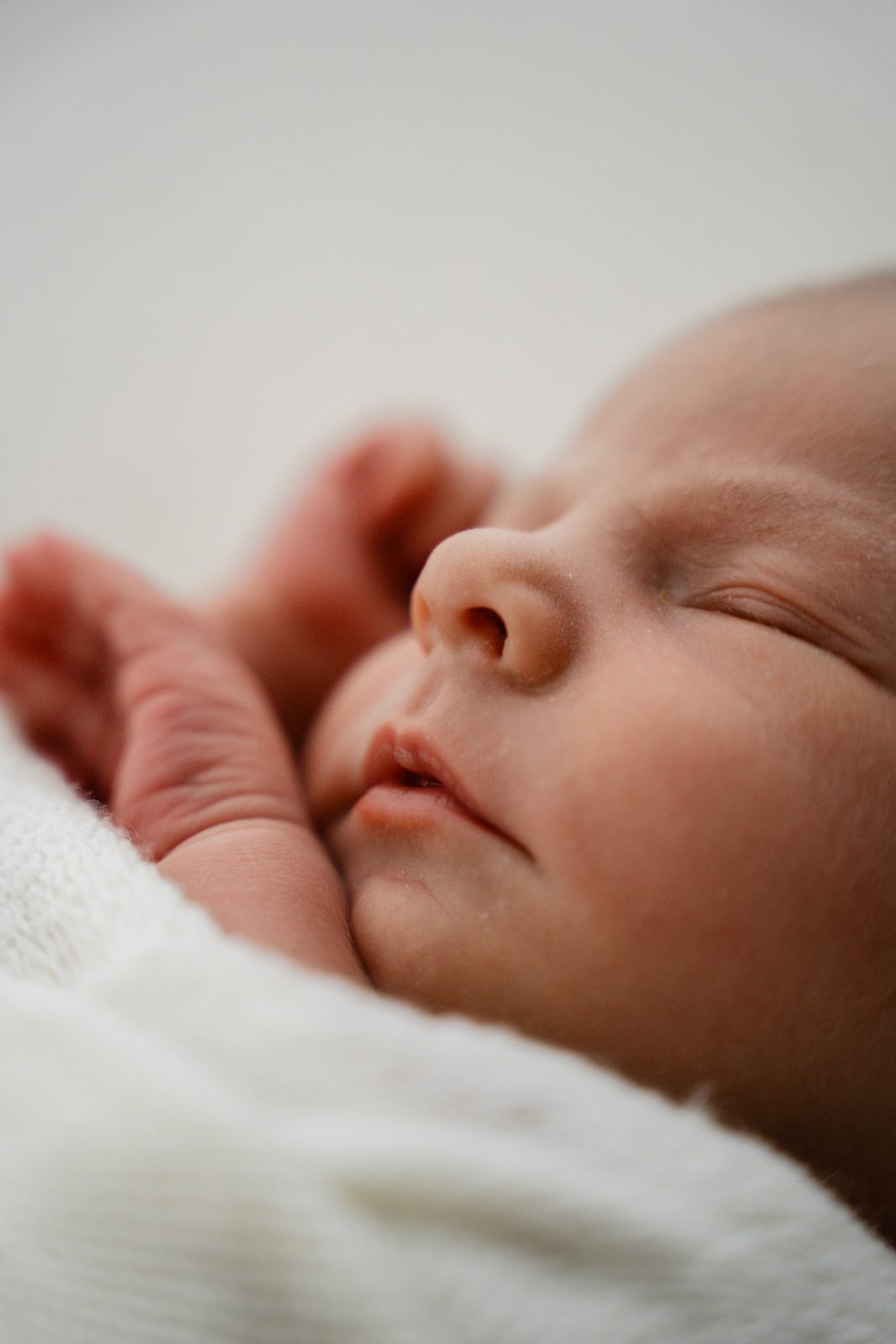 Close-up van een slapende newborn met handjes bij het gezicht